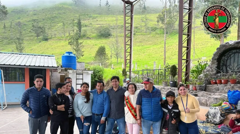 Grupo del Colegio posa en una zona rural con montañas verdes, durante una jornada de entrega de donaciones