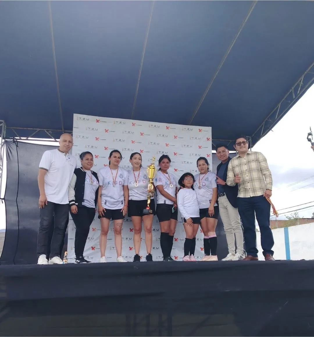 Premiación en el escenario: jugadoras con trofeo junto a los organizadores del campeonato
